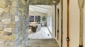 Un arco in pietra che dà accesso a un soggiorno con un divano, un tavolino e un quadro appeso al muro.