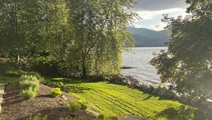 Paesaggio tranquillo di un lago, con vegetazione lussureggiante e un muro di pietra.