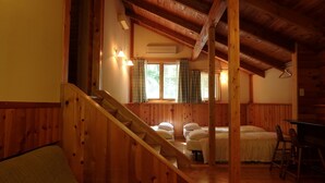 A wooden interior with a staircase leading to a bedroom area, a window with curtains, and a table with chairs. - Takara Onsen Pension Satchimo (Kitashiobara)