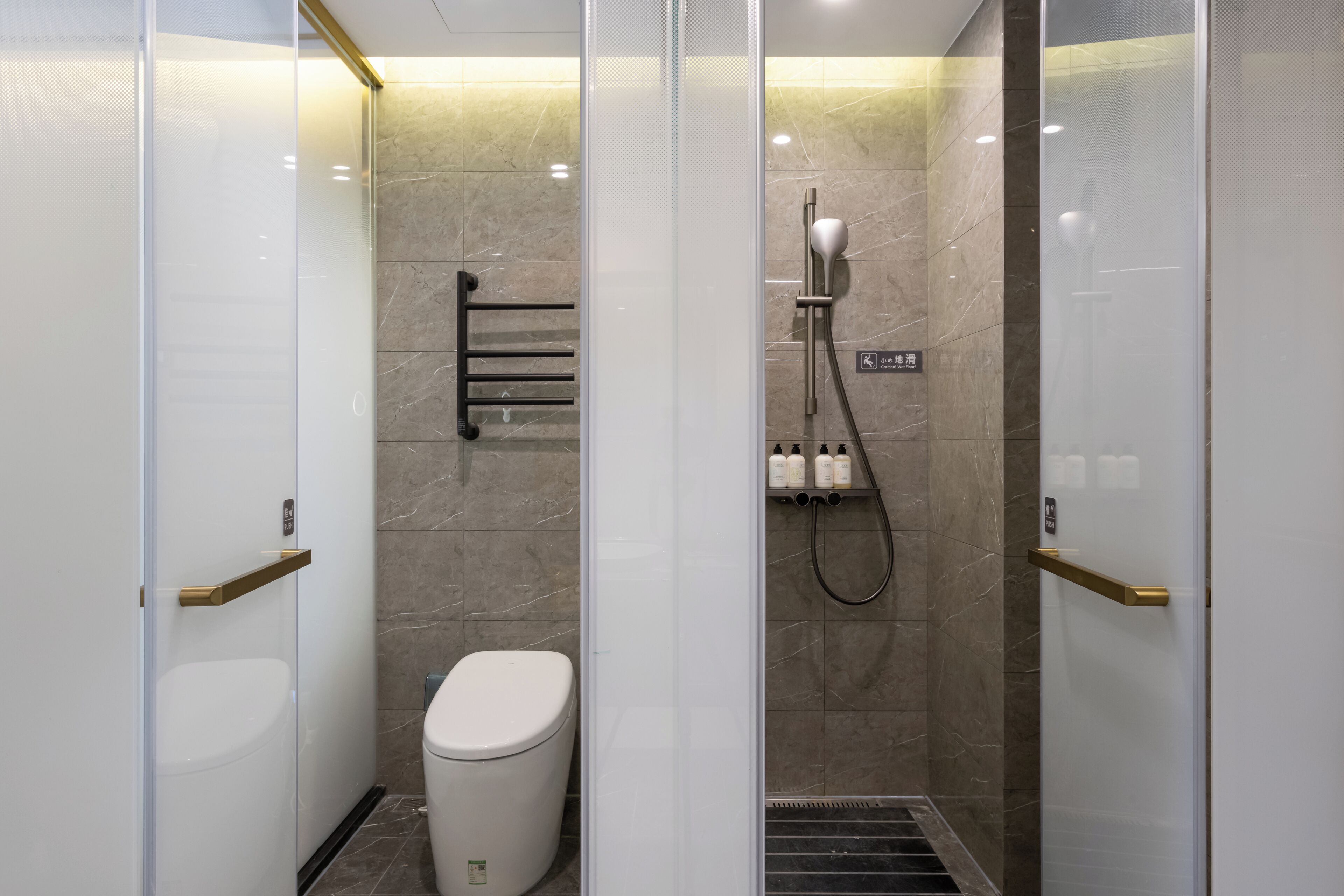 A modern bathroom with a toilet, a shower, and a glass-enclosed shower stall.