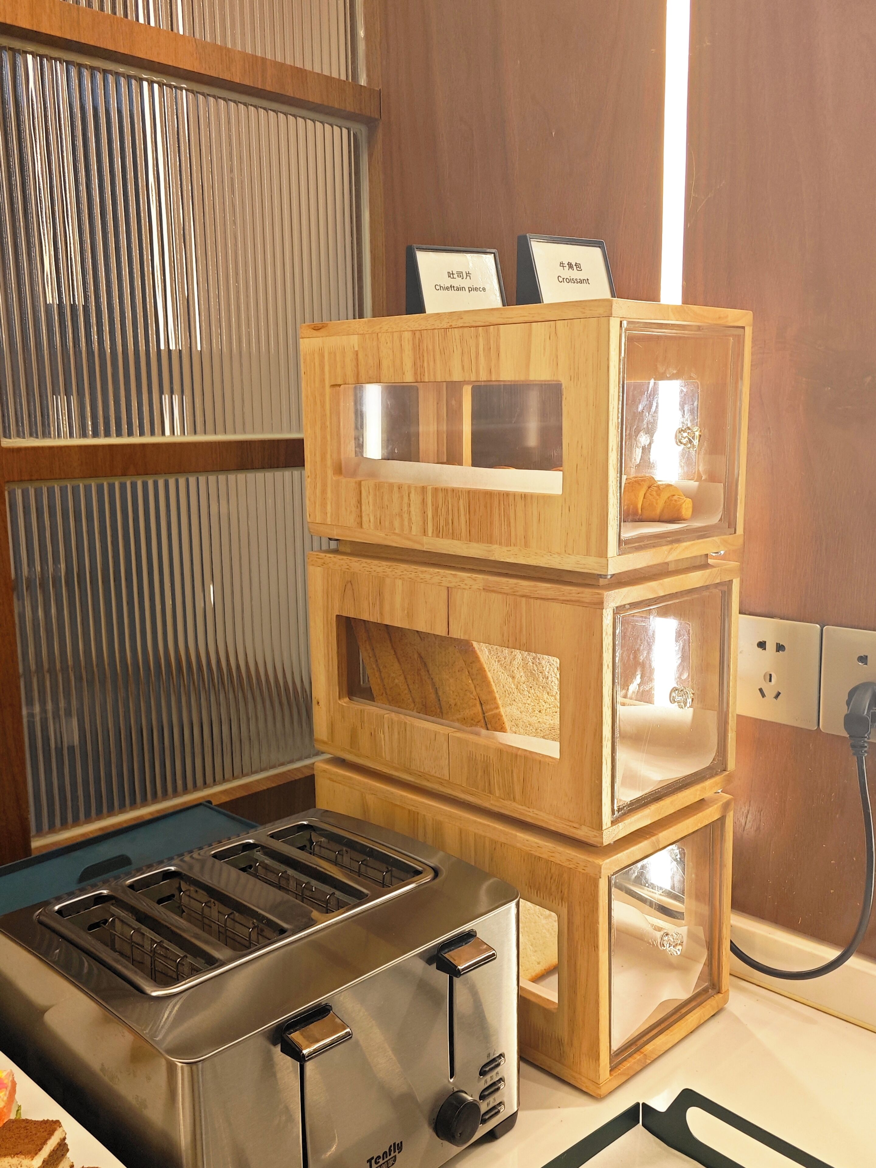 A kitchen with a toaster and a wooden bread box with labels.