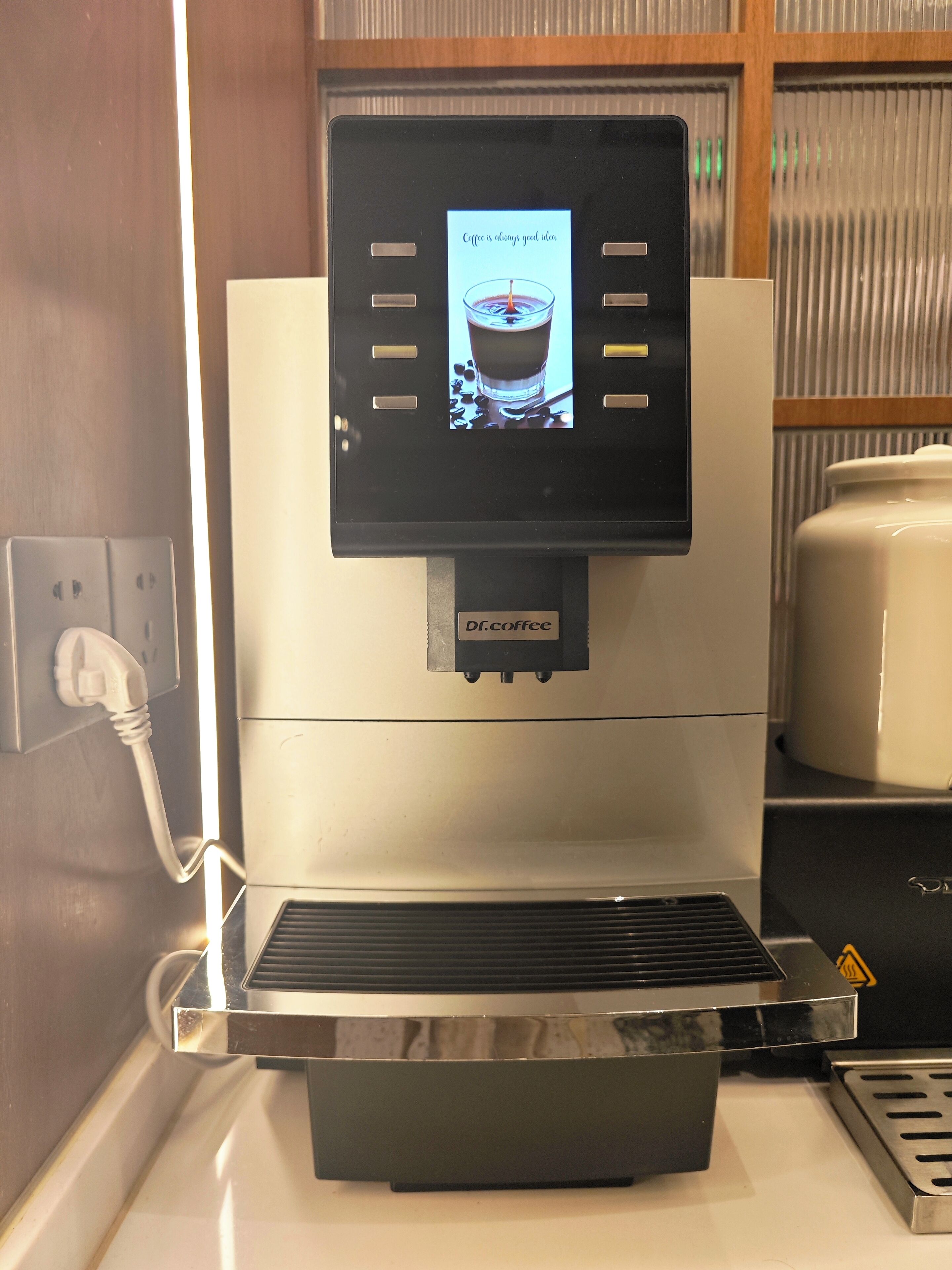 Eine Kaffeemaschine mit digitalem Display, einer Steckdose und einer Kaffeekanne.