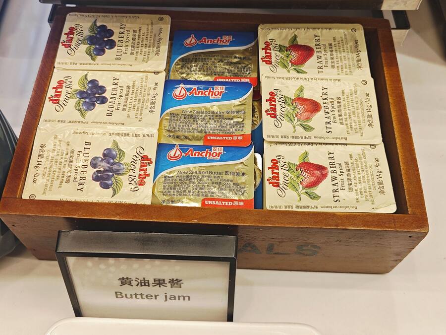 A wooden box containing various types of fruit spreads and butter jam.