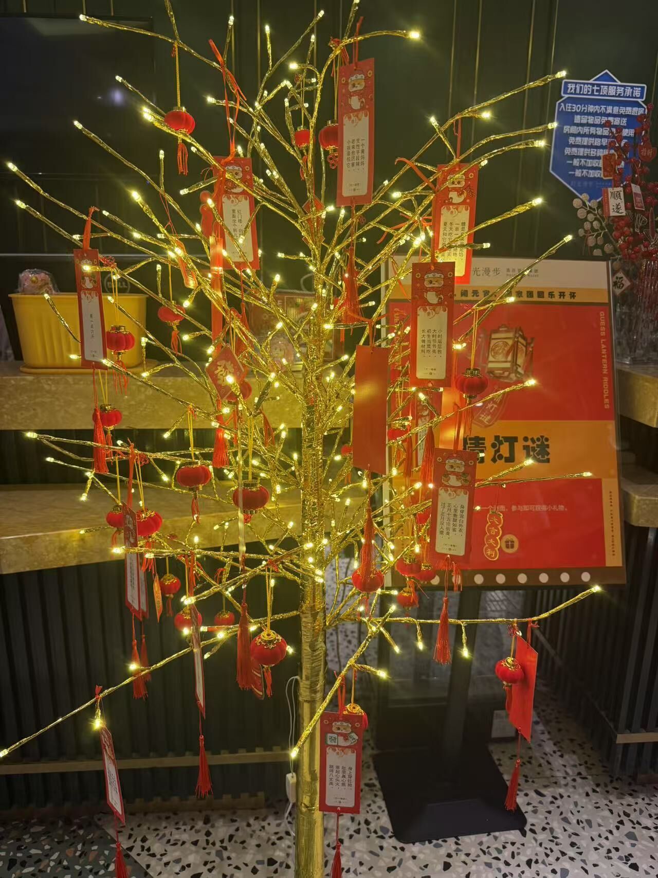 Un árbol decorativo con luces y adornos rojos, rodeado de estanterías con diversos objetos.