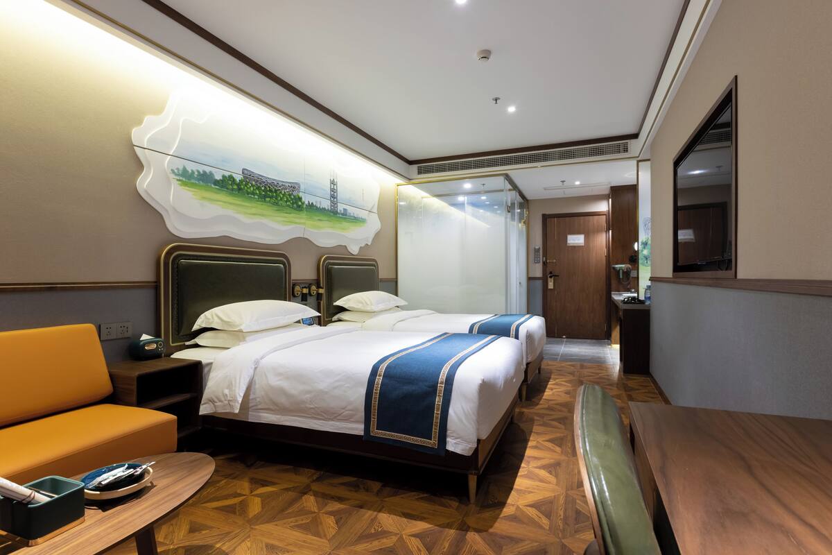 Une chambre d’hôtel avec deux lits, un canapé, une table à manger et une grande fenêtre.