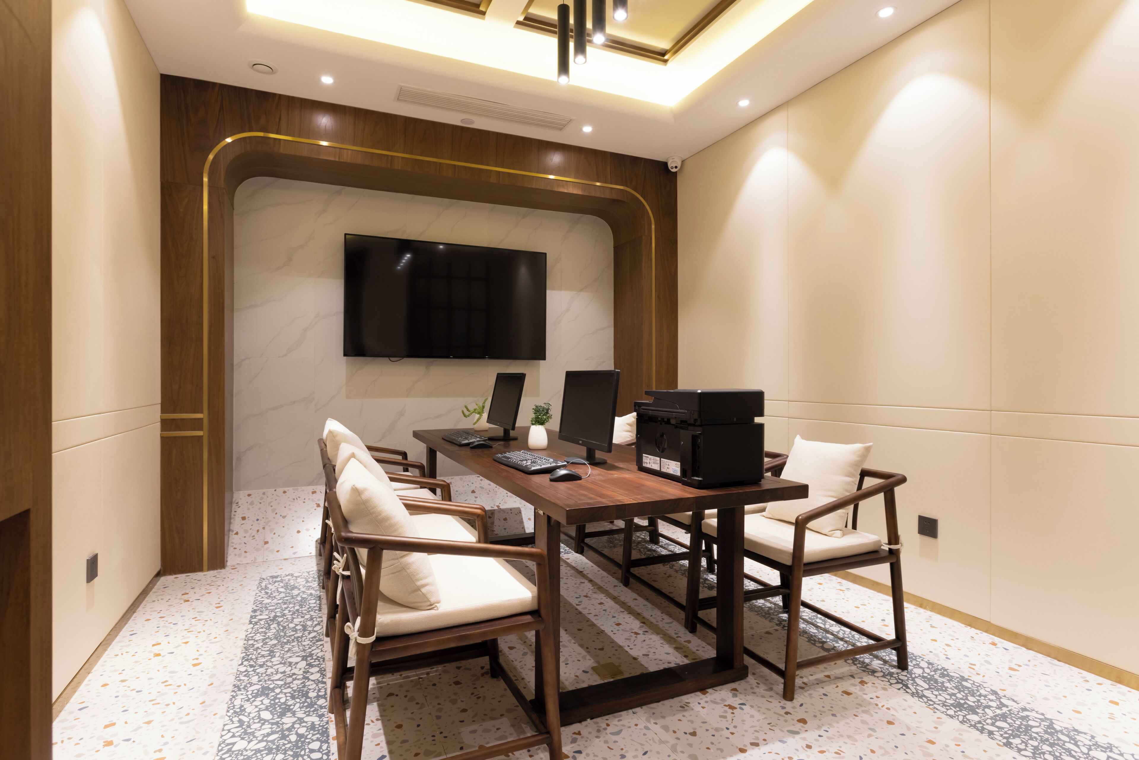 A conference room with a large flat-screen TV, a printer, and two computer monitors.
