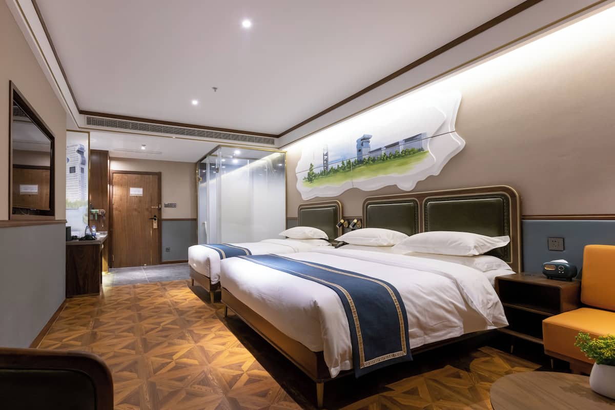 Une chambre d’hôtel avec un grand lit, un bureau, une chaise et une petite table sur laquelle est posée une plante.