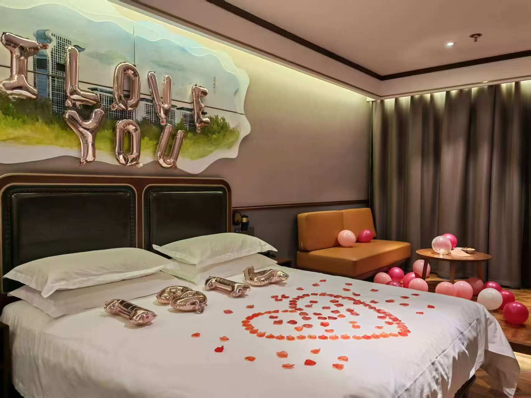 Une chambre d’hôtel avec un lit, un canapé et une petite table décorée de ballons.