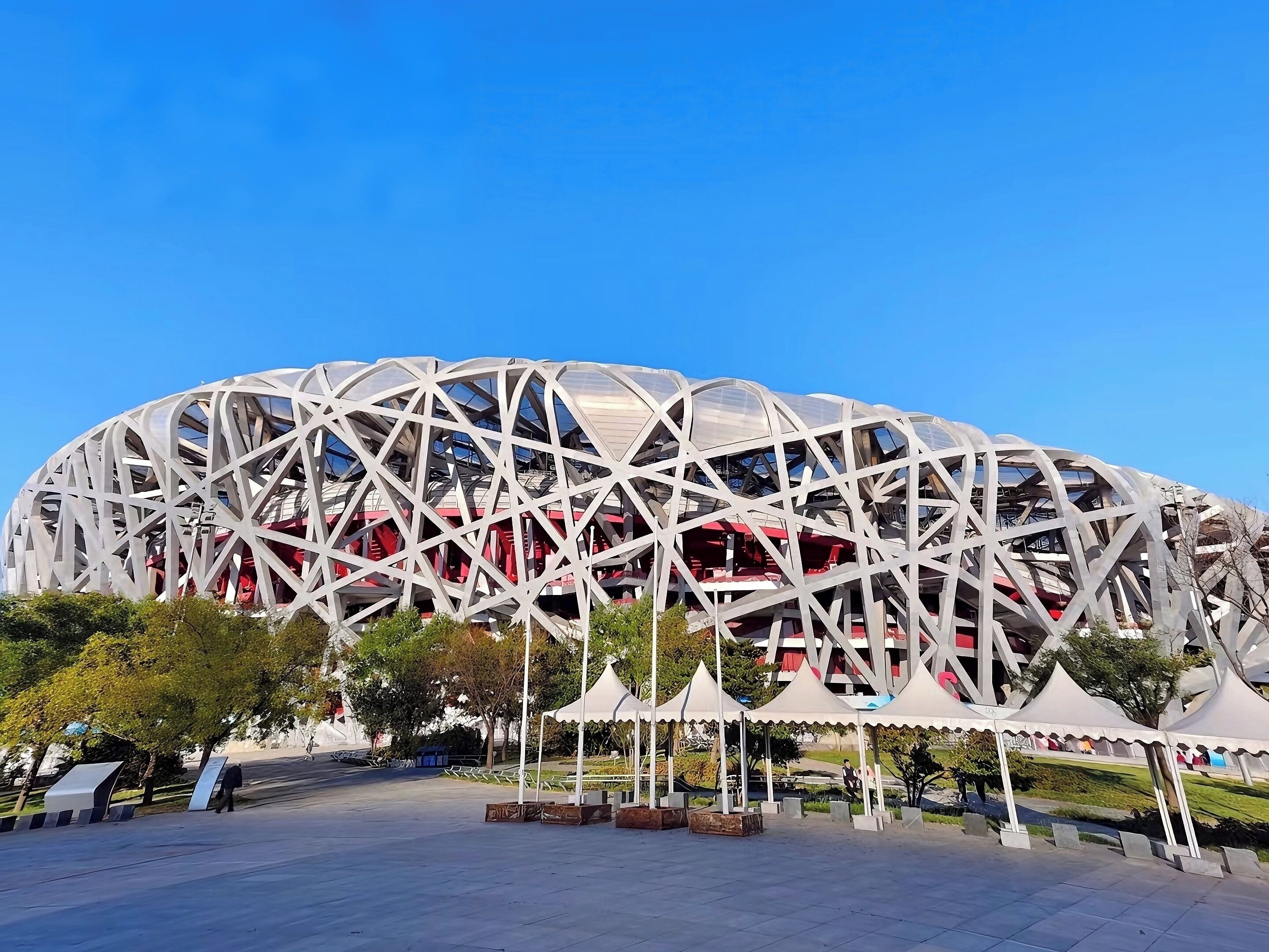Un estadio con un diseño geométrico distintivo, rodeado de espacios abiertos y árboles.