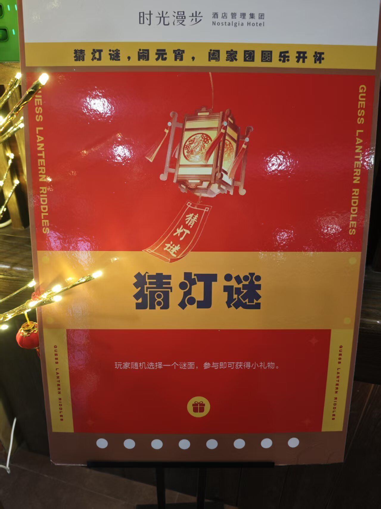 A sign for Guess Lantern Riddles at Nostalgia Hotel, featuring a lantern puzzle game.