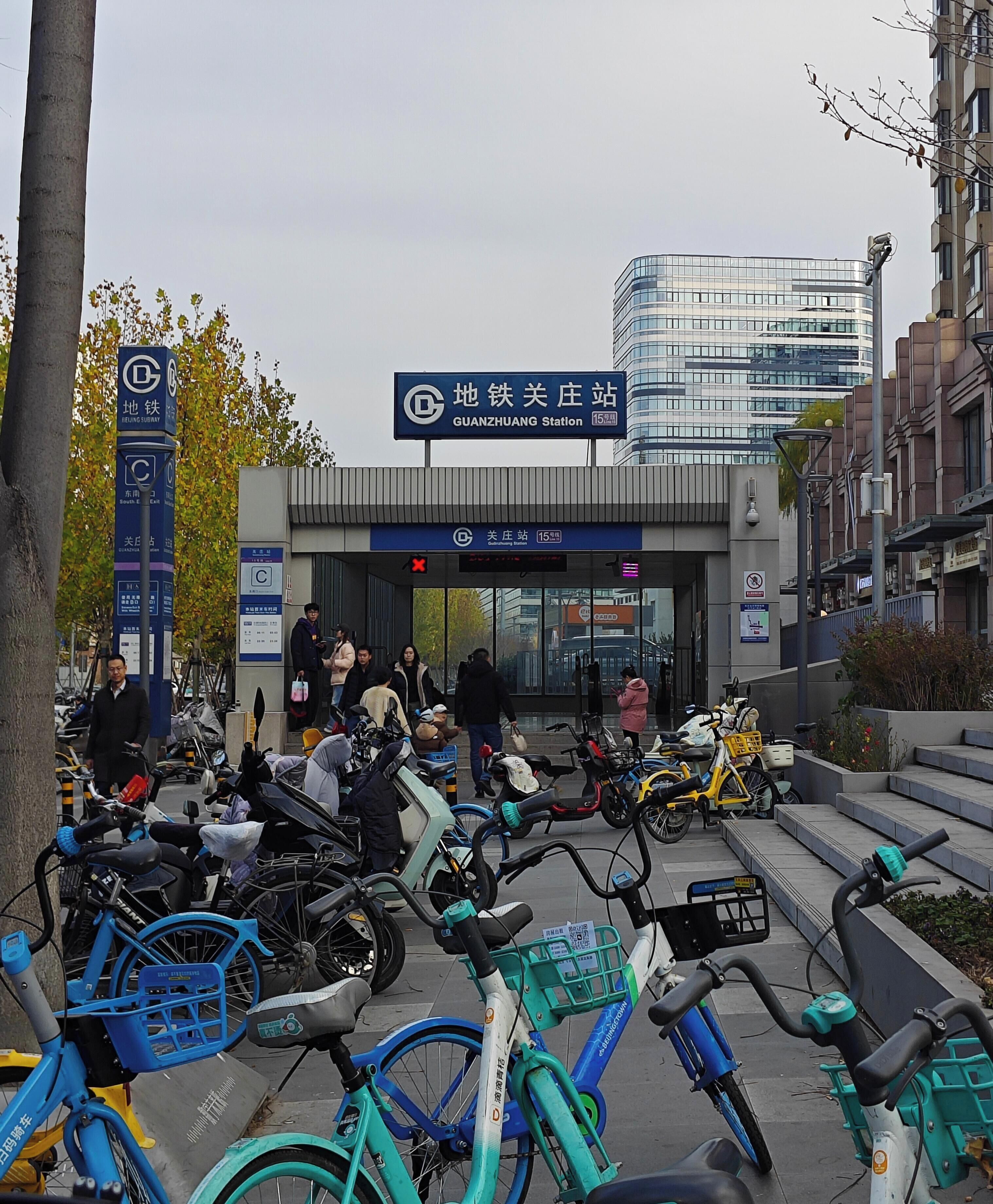 A bicycle parking area with several bicycles and a sign for Guanzhuang Station.