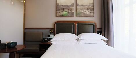 A hotel room with a bed, a desk, and two paintings on the wall.