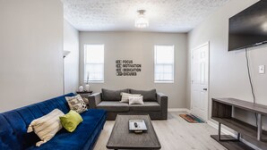 A modern living room with a blue sofa, grey couch, and a coffee table. - Grand Park, Westfield, Space For Entire Team, Sleeps 30 comfortably. Unit A (Sheridan)
