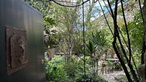 An outdoor garden area with stone walls, various plants, and outdoor seating. - La Bergerie (MIRABEL AUX BARONNIES)
