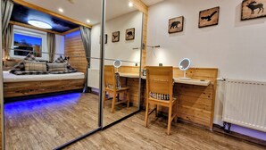 Ein gemütliches Zimmer mit einem Bett, einem Schreibtisch mit Spiegel und einem großen Spiegel an der Wand.