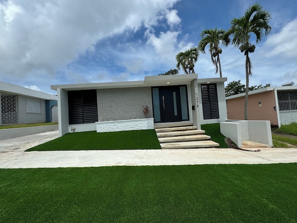 A modern house with a flat roof, a black door, and a number 1278 on the wall.