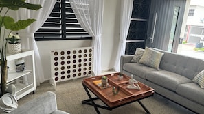 A modern living room with a grey sofa, a wooden coffee table, and a white radiator.