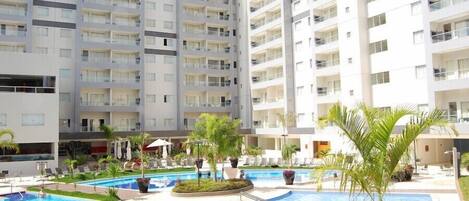 Um hotel moderno com vários andares, uma piscina central e áreas de estar ao ar livre.