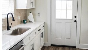 A kitchen with white cabinets, a stainless steel sink, and a wooden floor. - Short drive to the beautiful 30-A beaches!!
Cozy Riverwalk Landing Cottage 2-B (Freeport)