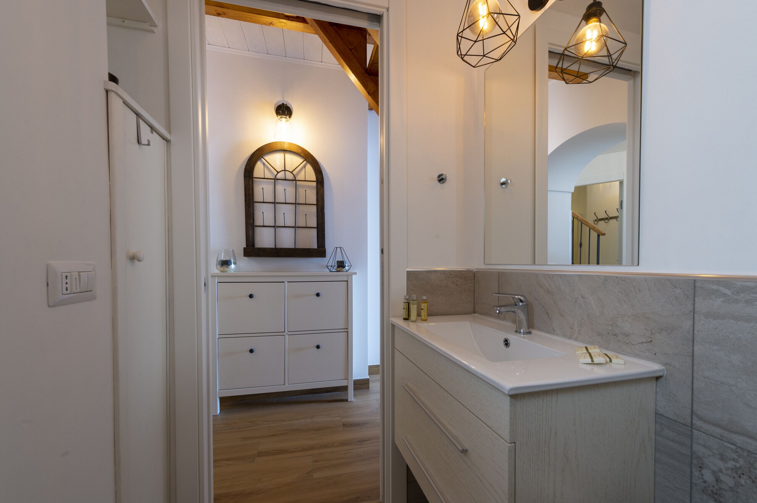 A modern bathroom with a large mirror, a sink, and a vanity with drawers.
