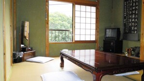 Habitació japonesa tradicional amb fusta de tatami, una taula de fusta baixa, televisió i un panell shoji.