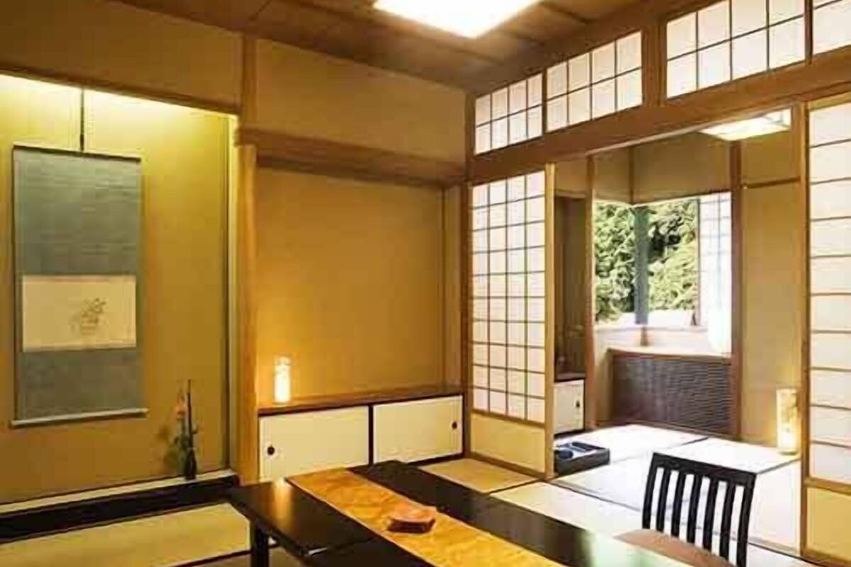 Una habitación japonesa tradicional con suelo de tatami, una mesa baja y puertas correderas.