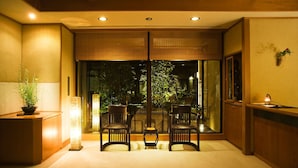 A room with a sliding glass door, two chairs, a small table, a potted plant, and a lamp. - Yuwaku Onsen Sakaeya Ryokan (Kanazawa)