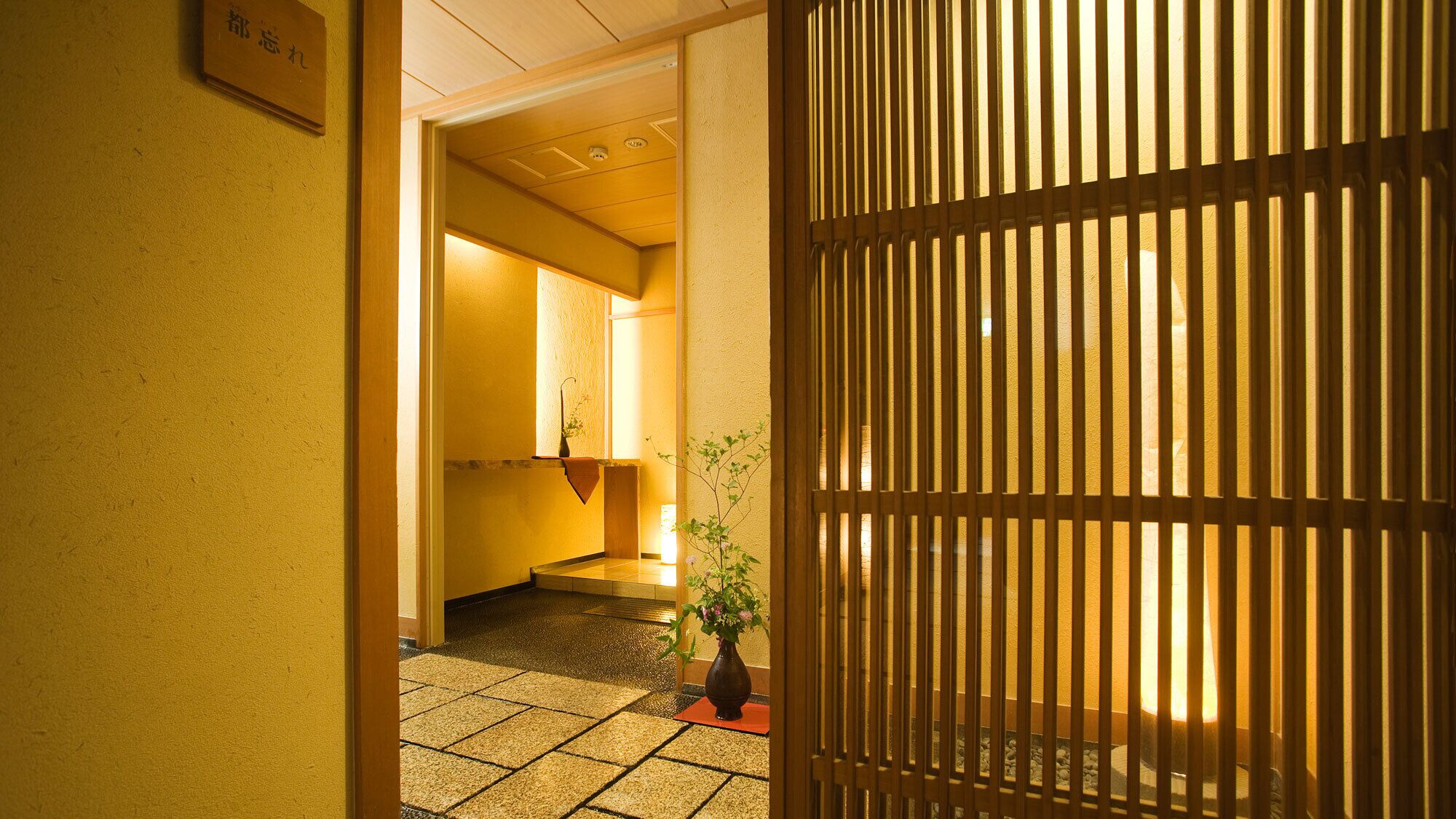 Ein Flur mit traditionellem japanischen Shoji-Bildschirm, Fliesenboden und einem Blumentopf.