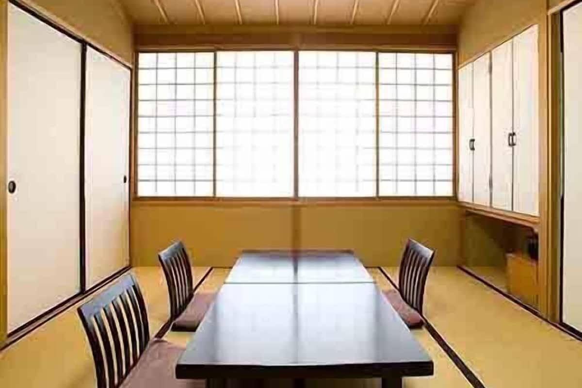 Una habitación tradicional japonesa con suelo de tatami, una mesita baja y puertas correderas.