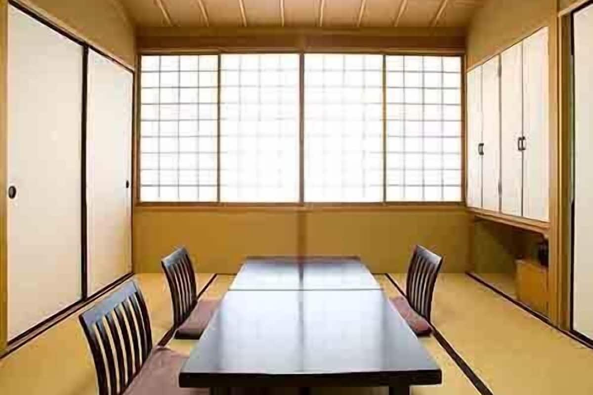 Una habitación japonesa tradicional con suelo de tatami, una mesa baja y puertas correderas.
