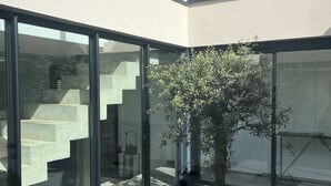 A modern building with large glass windows, a tree in the center, and a staircase leading to an upper level. - VILLA_DE_VACANCES_LA_PINATTE (Saint-Péray)