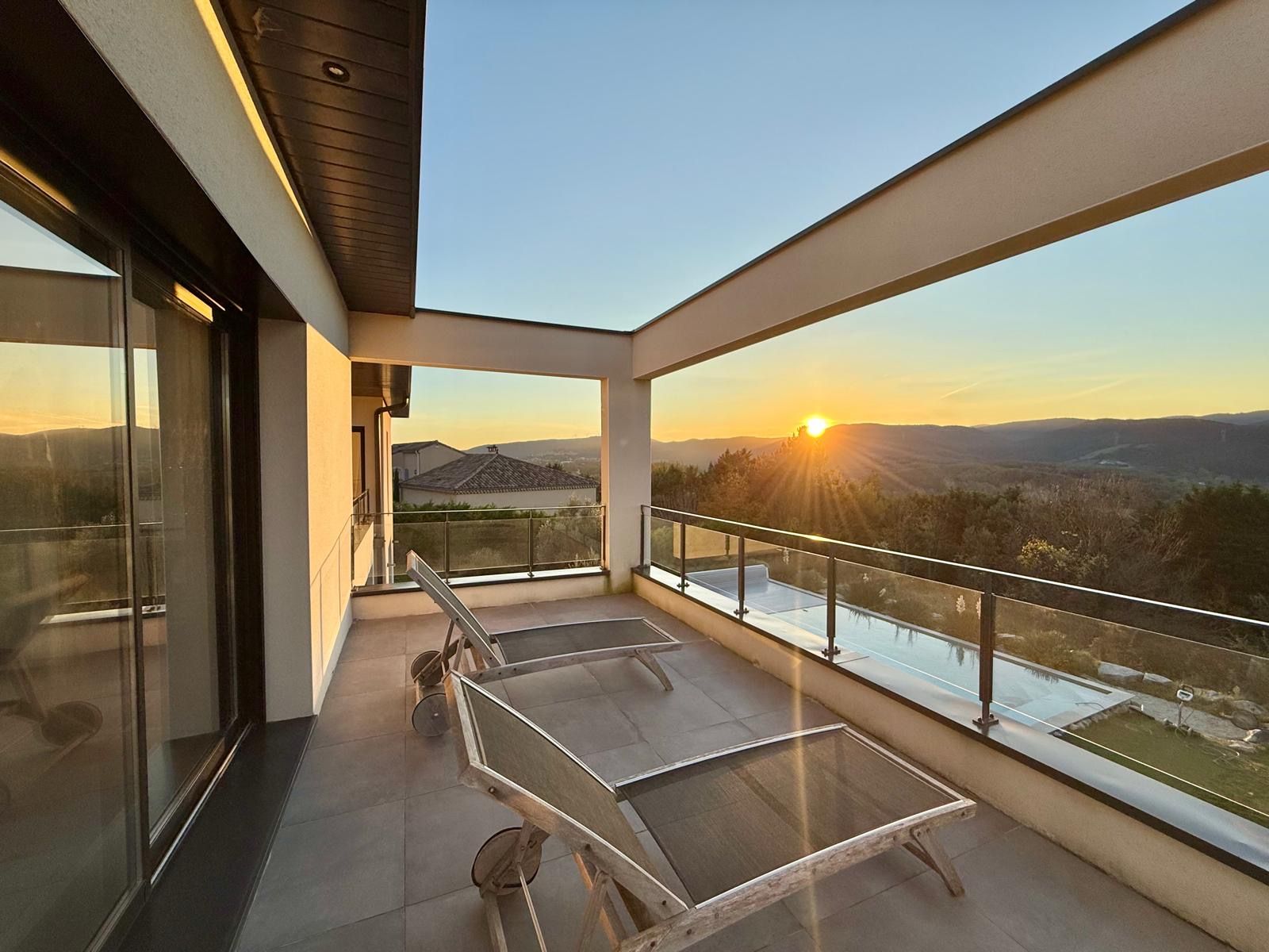 A balcony with a view of the sunset and mountains.