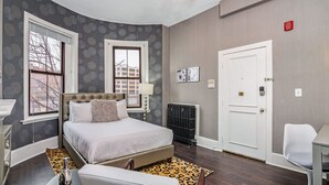 Ein Schlafzimmer mit einem Bett, einem Sessel, einer Heizung und einer Tür.
