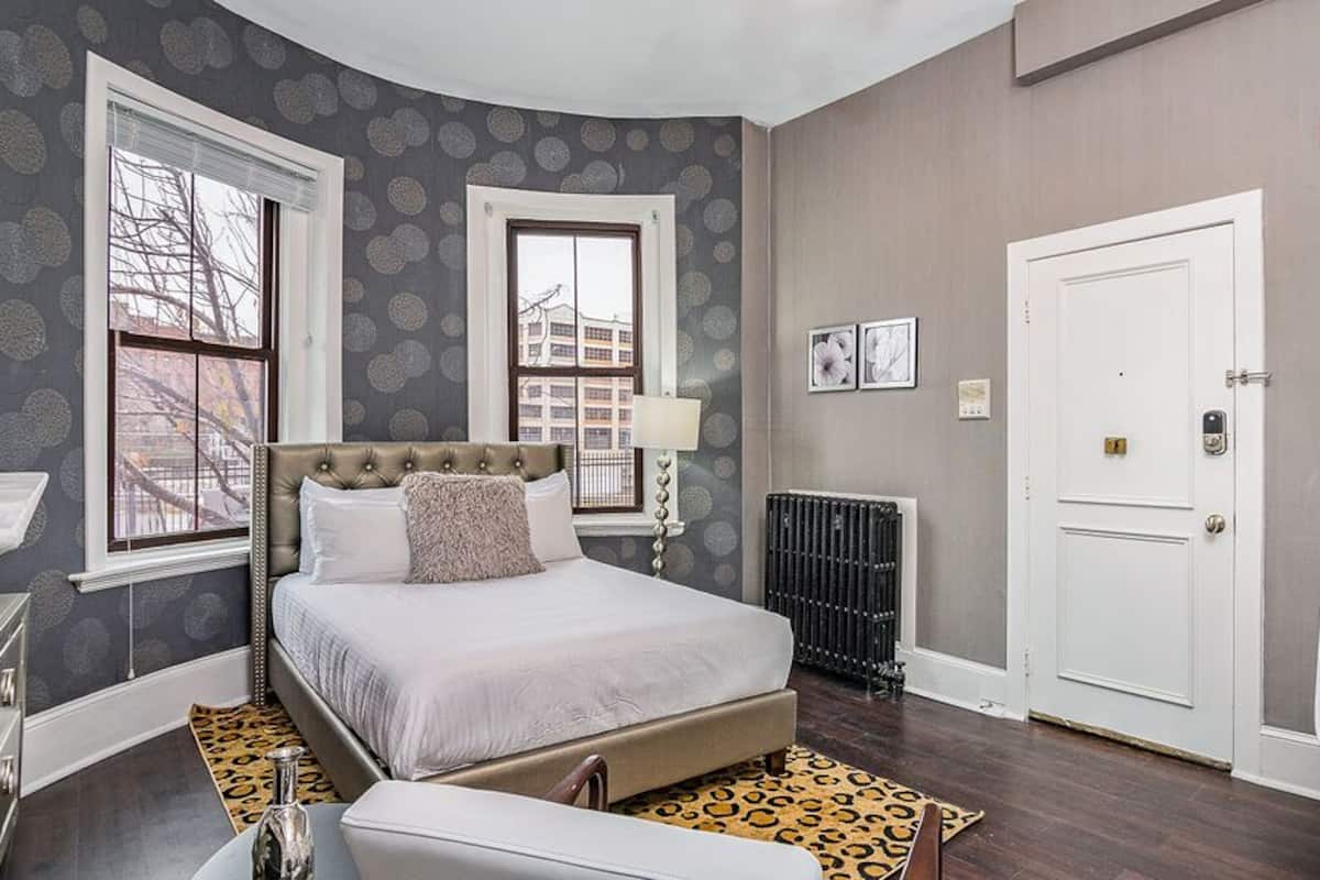 A bedroom with a bed, a chair, a radiator, and a door.
