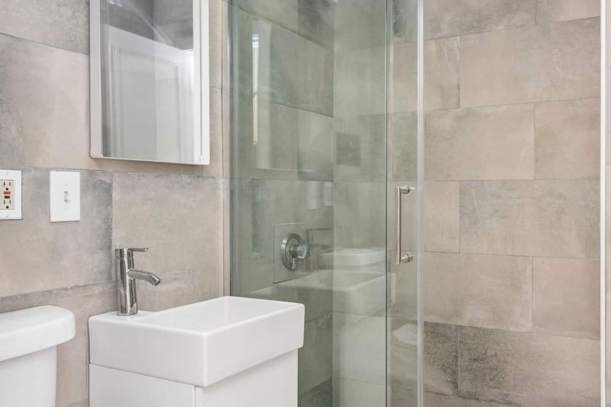 A modern bathroom with a glass shower enclosure, a white sink, and a mirror above the sink.