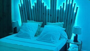 A bed with white linens and pillows, a wooden headboard with vertical slats, and two bedside lamps on a nightstand. - Vigets Balou (Fort-de-France)