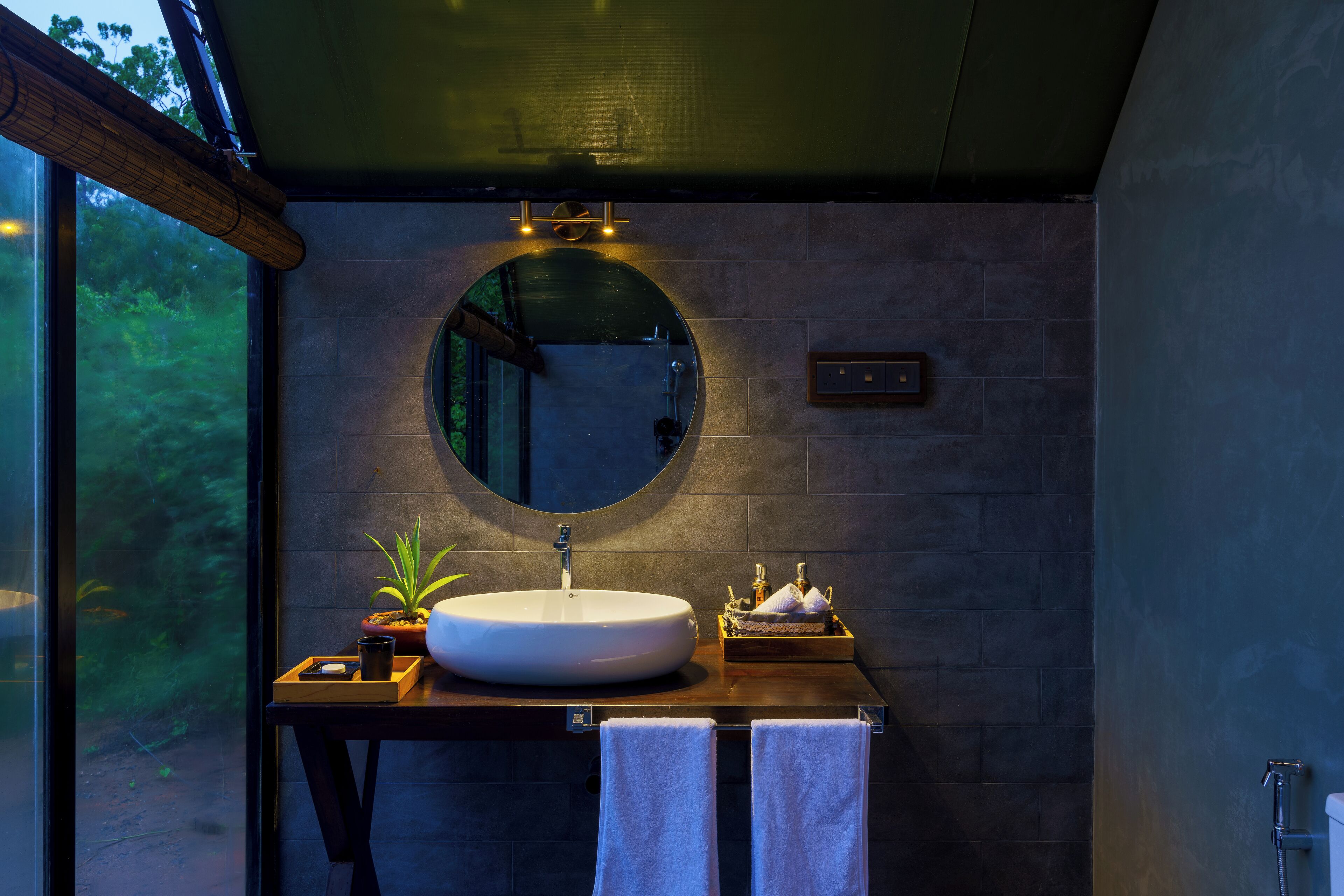 A modern bathroom with a round mirror, a large sink, and a wooden vanity.