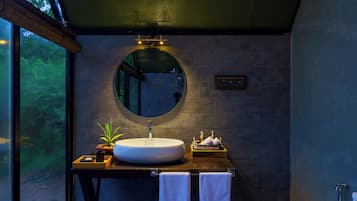 Un baño moderno con un espejo redondo, un lavabo grande y un mueble de tocador de madera.
