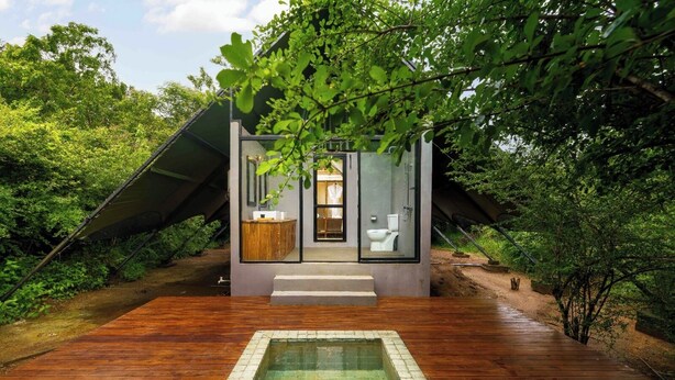A modern, glass-walled bathroom with a wooden deck leading to a small pool. - Makini Bush Camp (Kataragama)