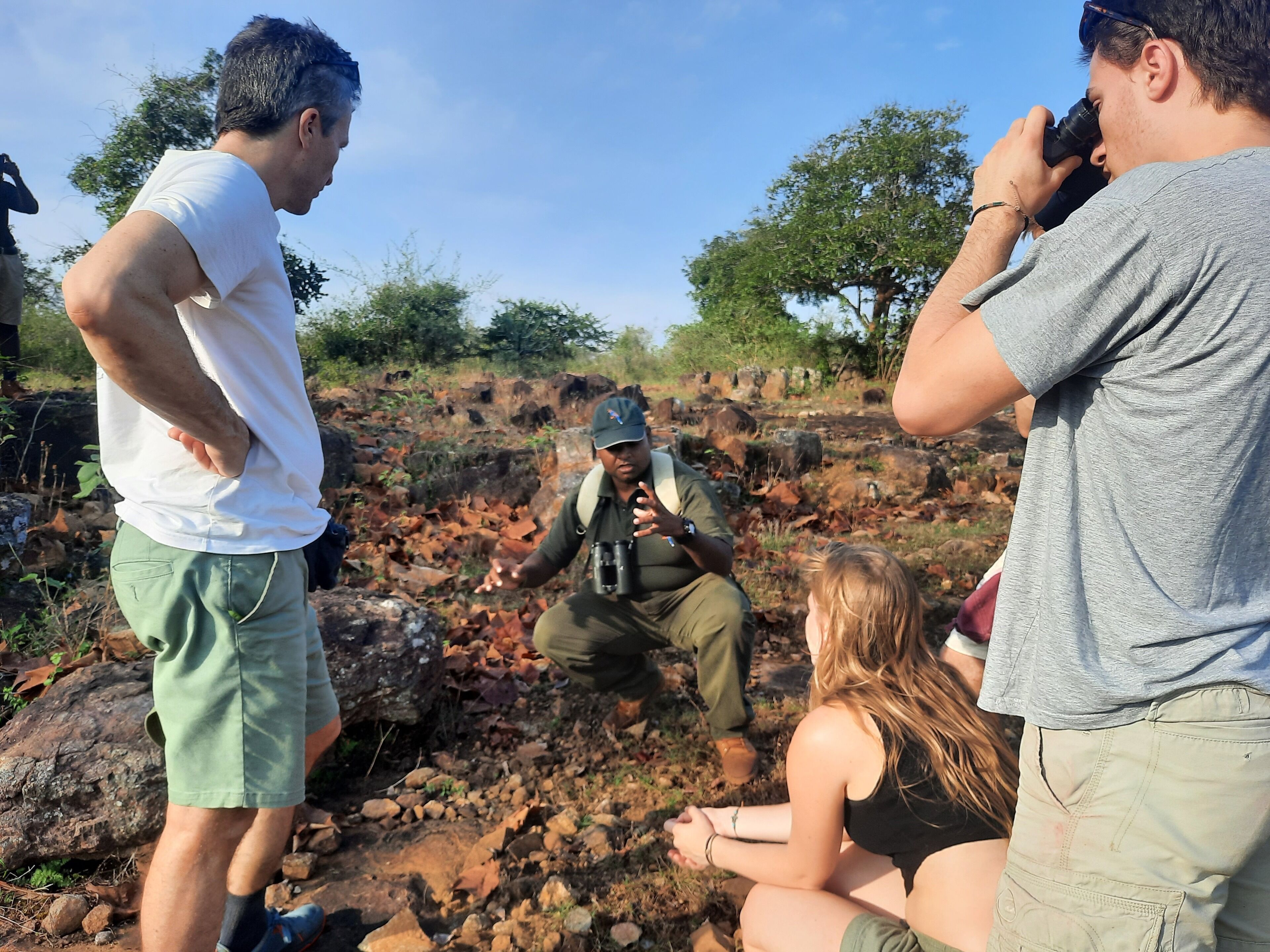A group of people outdoors, some taking photographs.