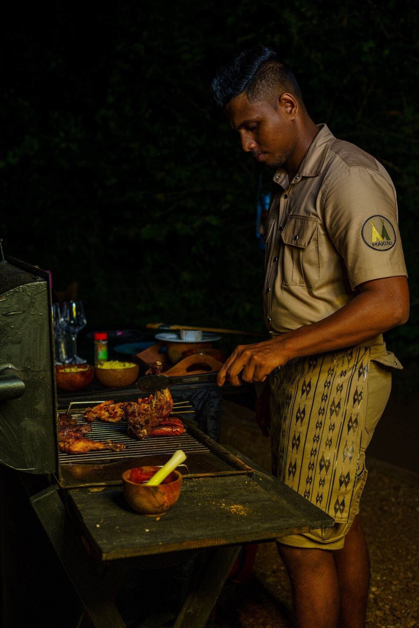 A person grilling food outdoors at night.