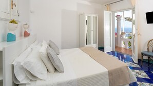 Une chambre à coucher avec un lit, une armoire, une chaise et un balcon offrant une vue.