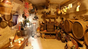 A rustic kitchen with wooden barrels, hanging pots, and various kitchen utensils.