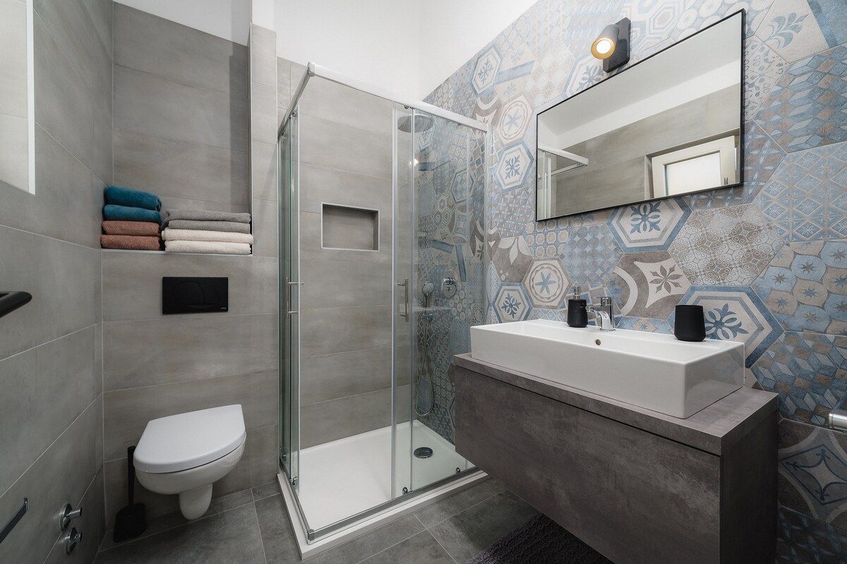 A modern bathroom with a glass shower enclosure, a white toilet, and a vanity with a mirror.