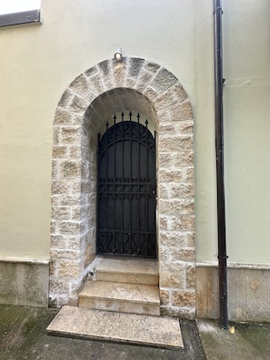 A stone archway leading to a black metal gate.