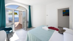 A hotel room with a bed, a chair, a balcony with a view, and a painting on the wall. - Villa Ecuba - Villa for Groups in a Strategic Position (Praiano)