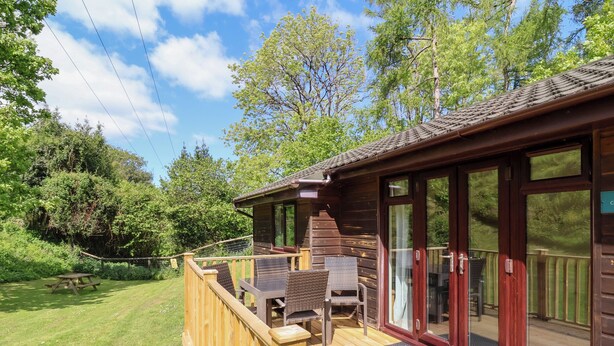 A wooden cabin with a deck, a picnic table, and a covered outdoor seating area. - 6 Manleigh Park (Ilfracombe)