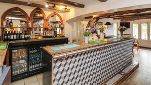 A bar area with a counter, shelves of bottles, and a refrigerator. - 6 Manleigh Park (Ilfracombe)