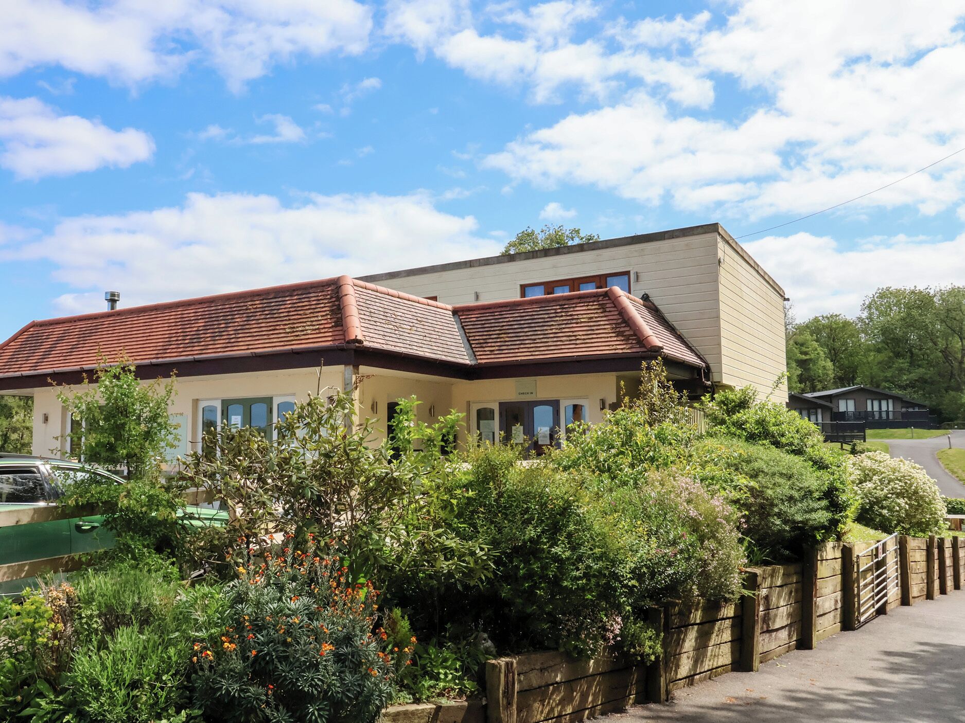 A two-story building with a red-tiled roof and a garden in front.