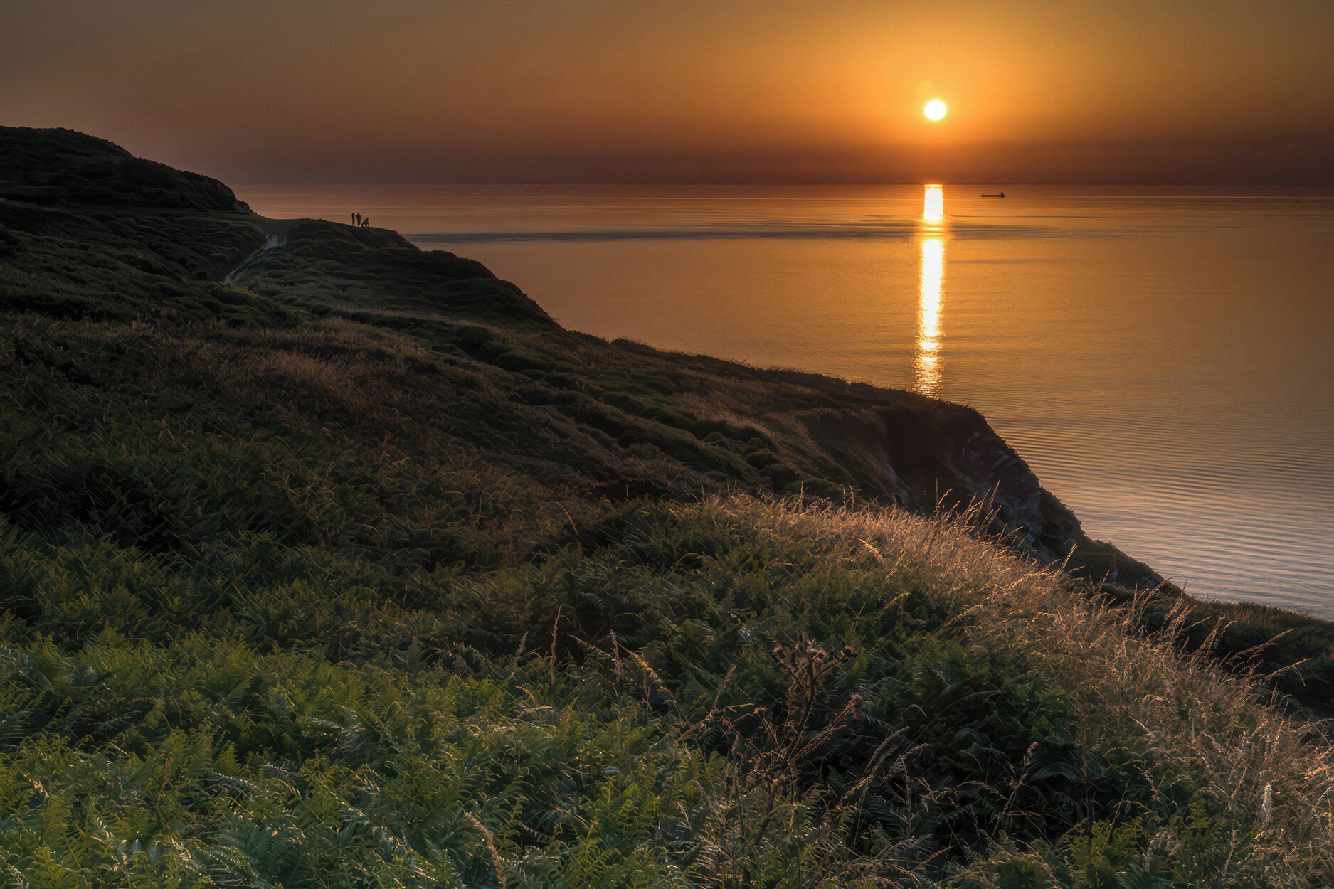 Un paisaje costero con atardecer, acantilados y un mar tranquilo.